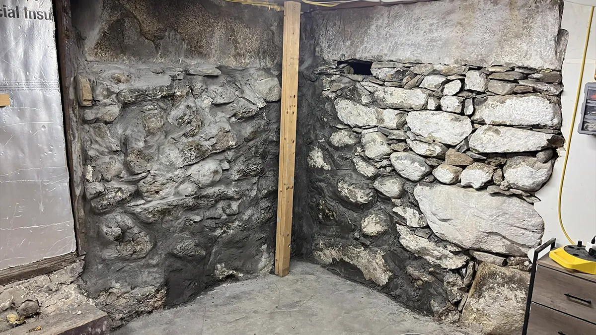 Fieldstone basement wall with worn mortar between the stones in an older home